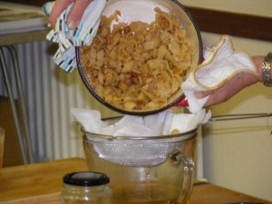 Line a stainless steel sieve with muslin or a tea towel and carefully drain the oil into a glass jug.